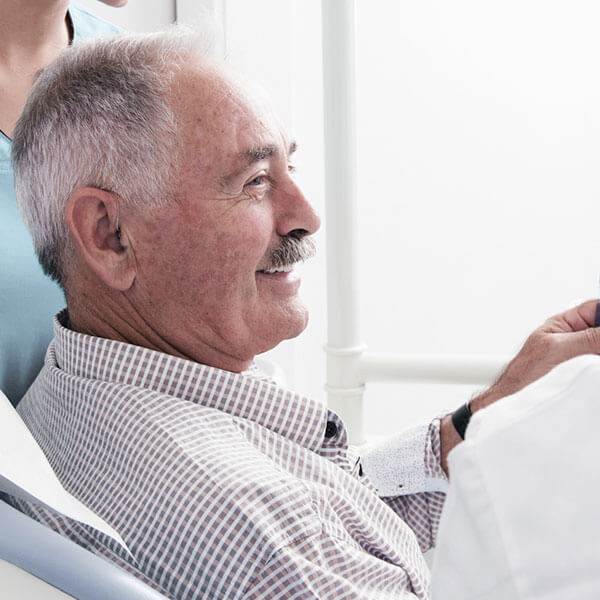 An elderly patient smiling at the Palms dental office while waiting for new dentures