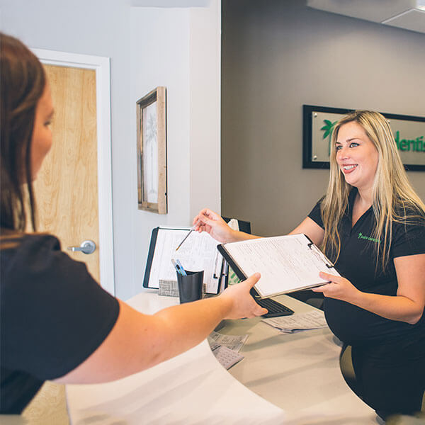 Our Palms Dentistry receptionist delivering a form to one of our new patients