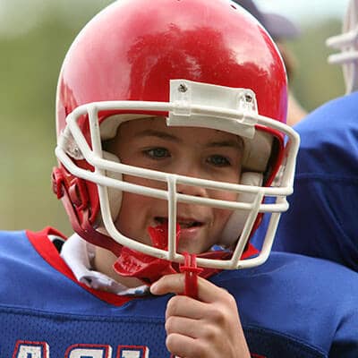 A child wearing an American Football helmet and his preventative dentistry mouthguard