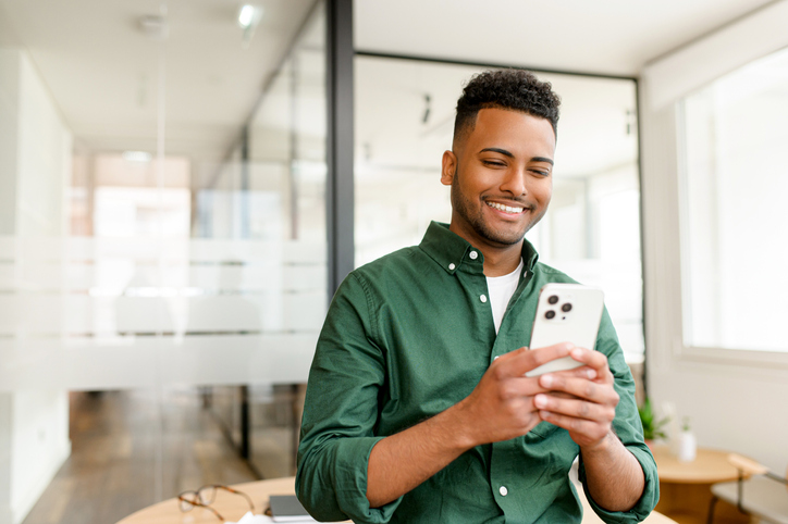 Confident man smiling while looking at his phone